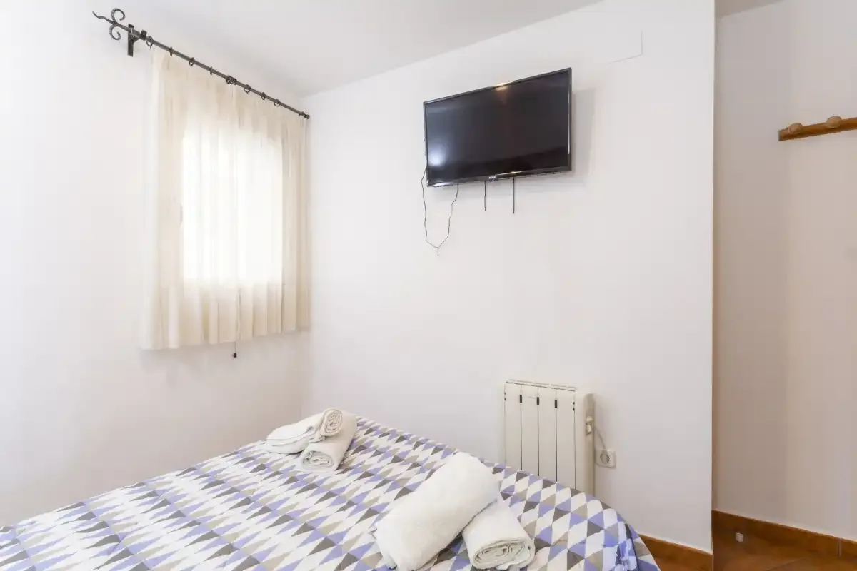 A bedroom with a patterned bedspread and a wall-mounted television.
