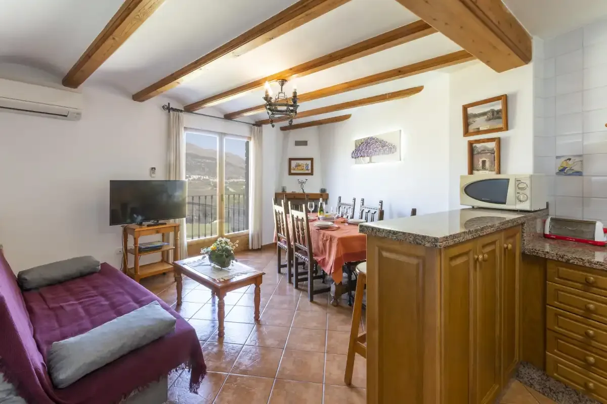 A living and dining area with a television, table, and kitchen counter.
