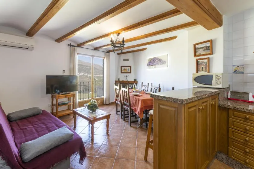 A combined living and dining area with a wooden kitchen counter and balcony doors.
