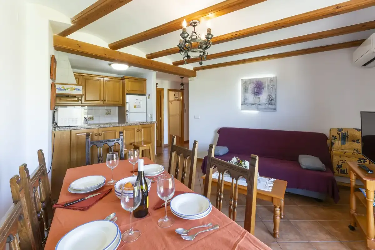 A dining and living area with a table, seating, and a compact kitchen.