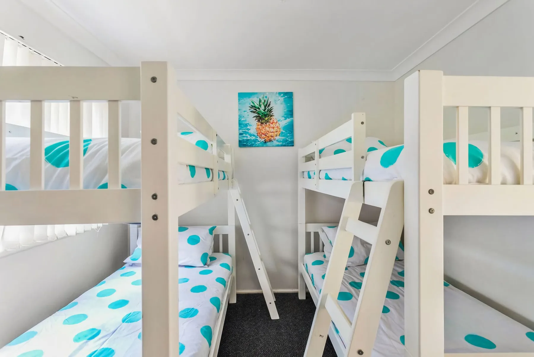 A bright bunk room with white beds and turquoise polka-dot bedding.