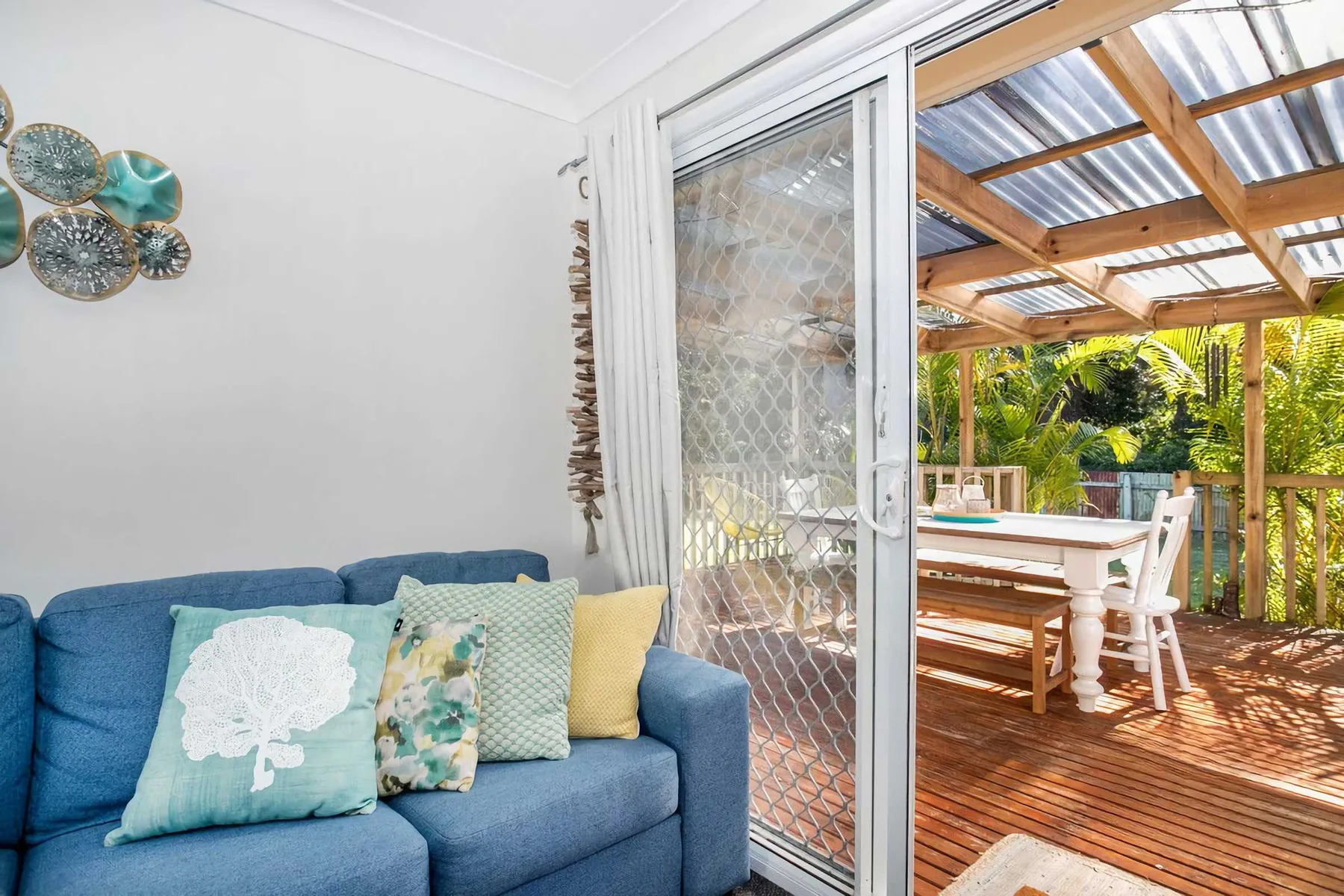 A living area with blue seating opens onto a covered wooden deck.
