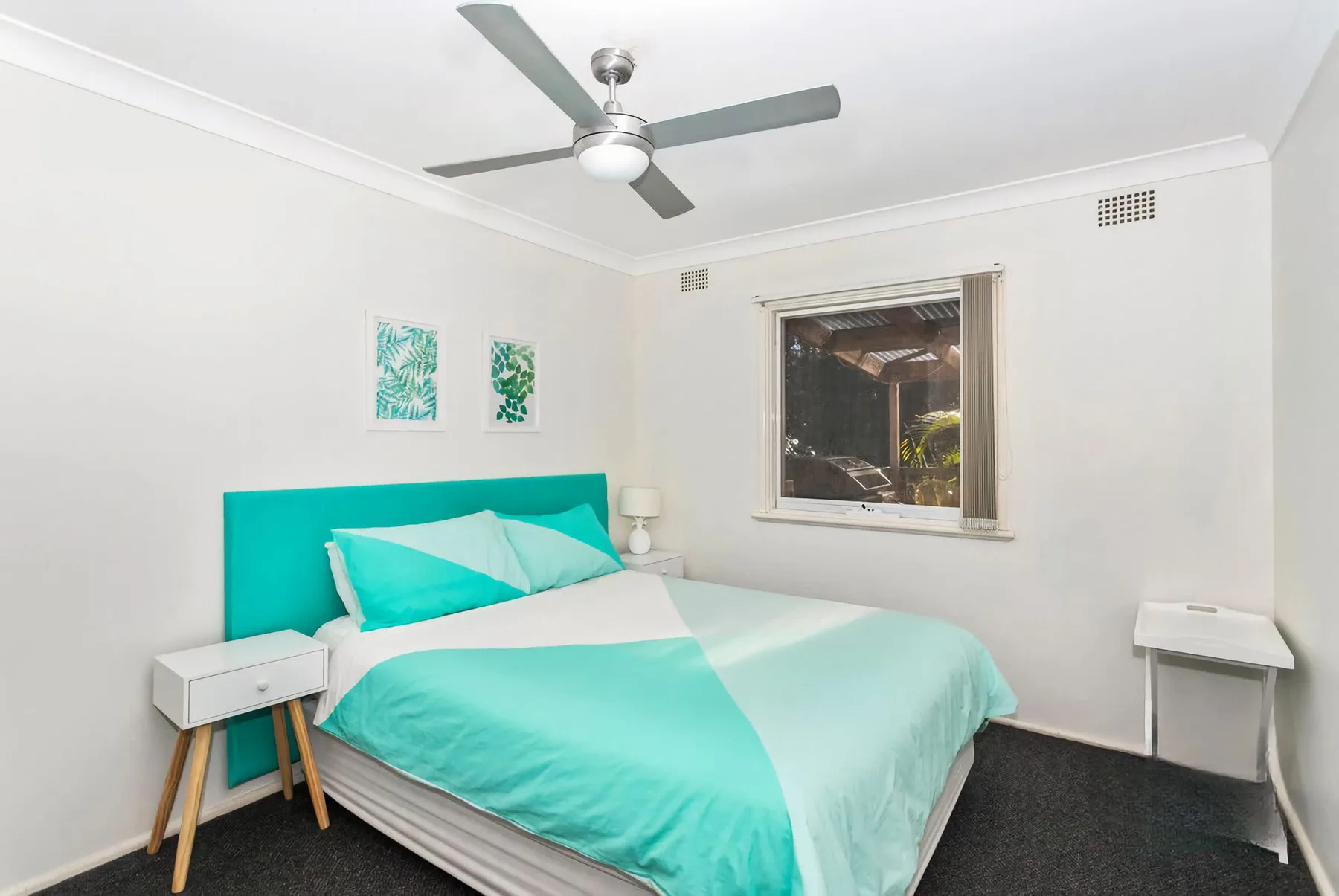 A bedroom with a bed dressed in turquoise and white bedding.