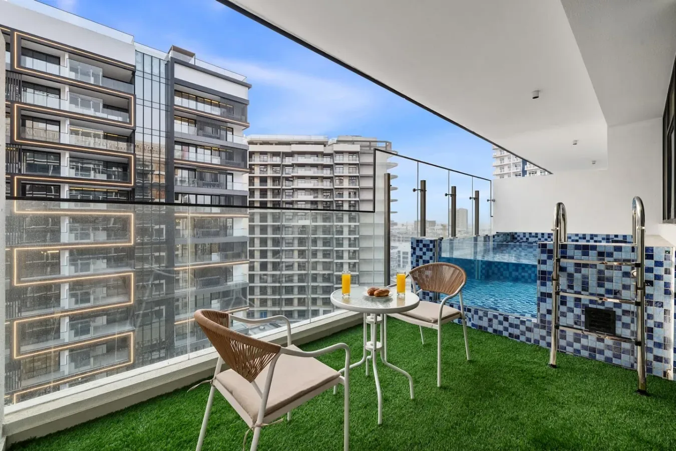 Una terraza en la azotea con asientos, césped artificial y una pequeña piscina revestida de azulejos.