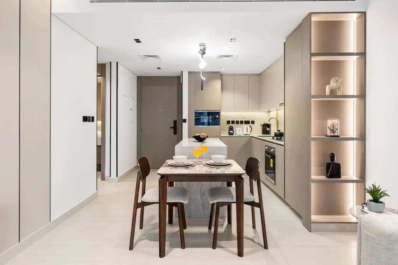 Un comedor con una mesa de madera y asientos, junto a una cocina compacta.