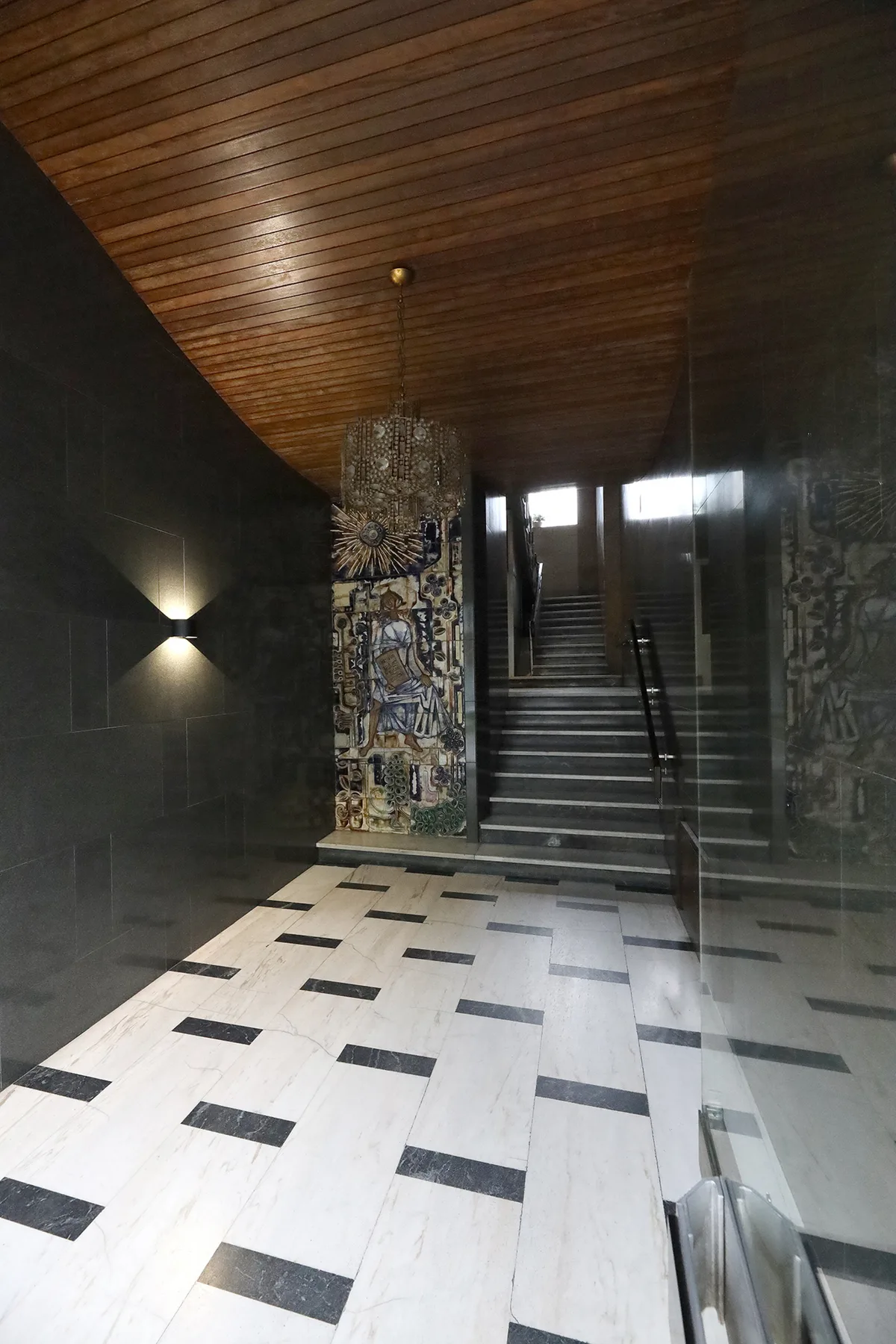 A tiled lobby opens onto a staircase, with a decorative panel beside the steps.