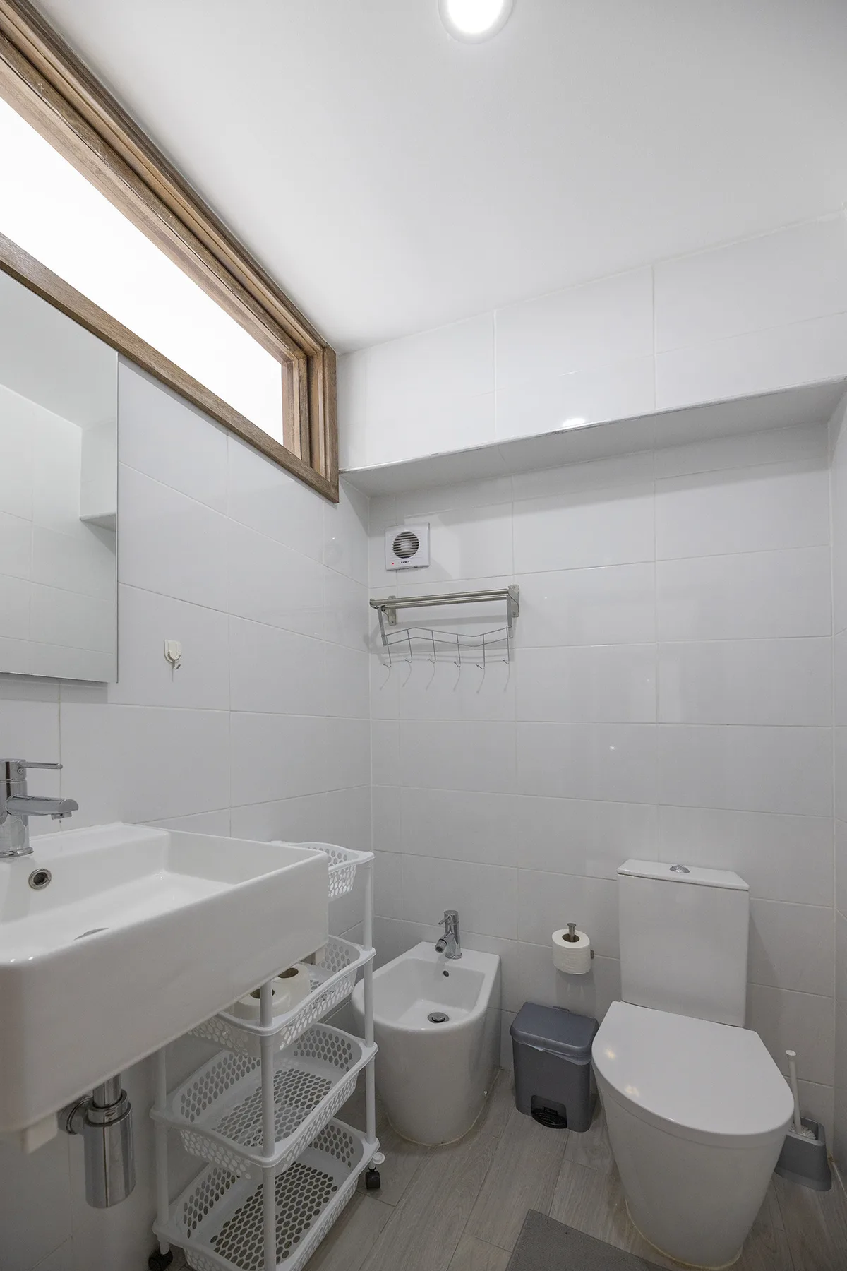 A tiled bathroom with a sink, toilet, and bidet.