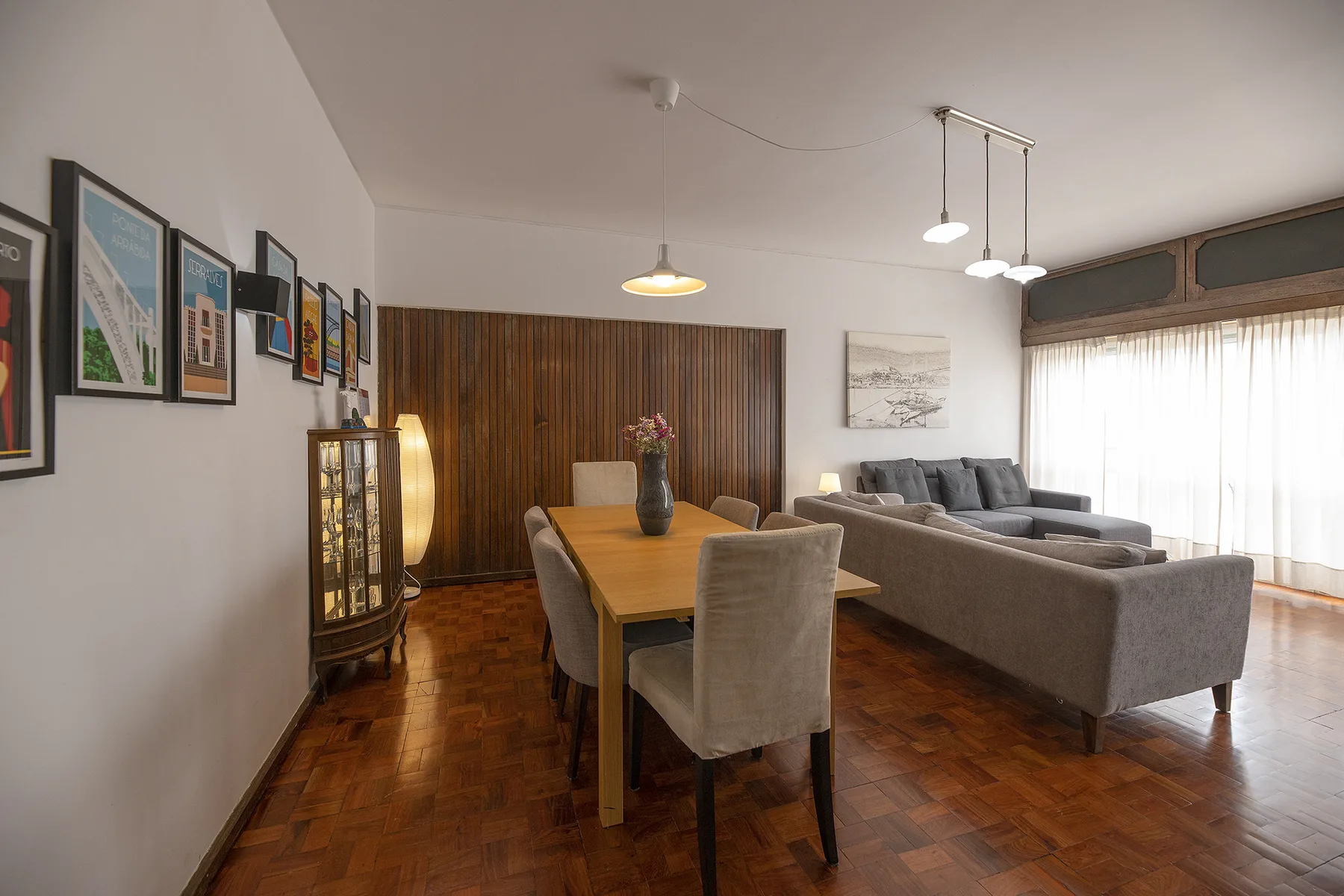 A dining and living area with a wooden table and upholstered seating.