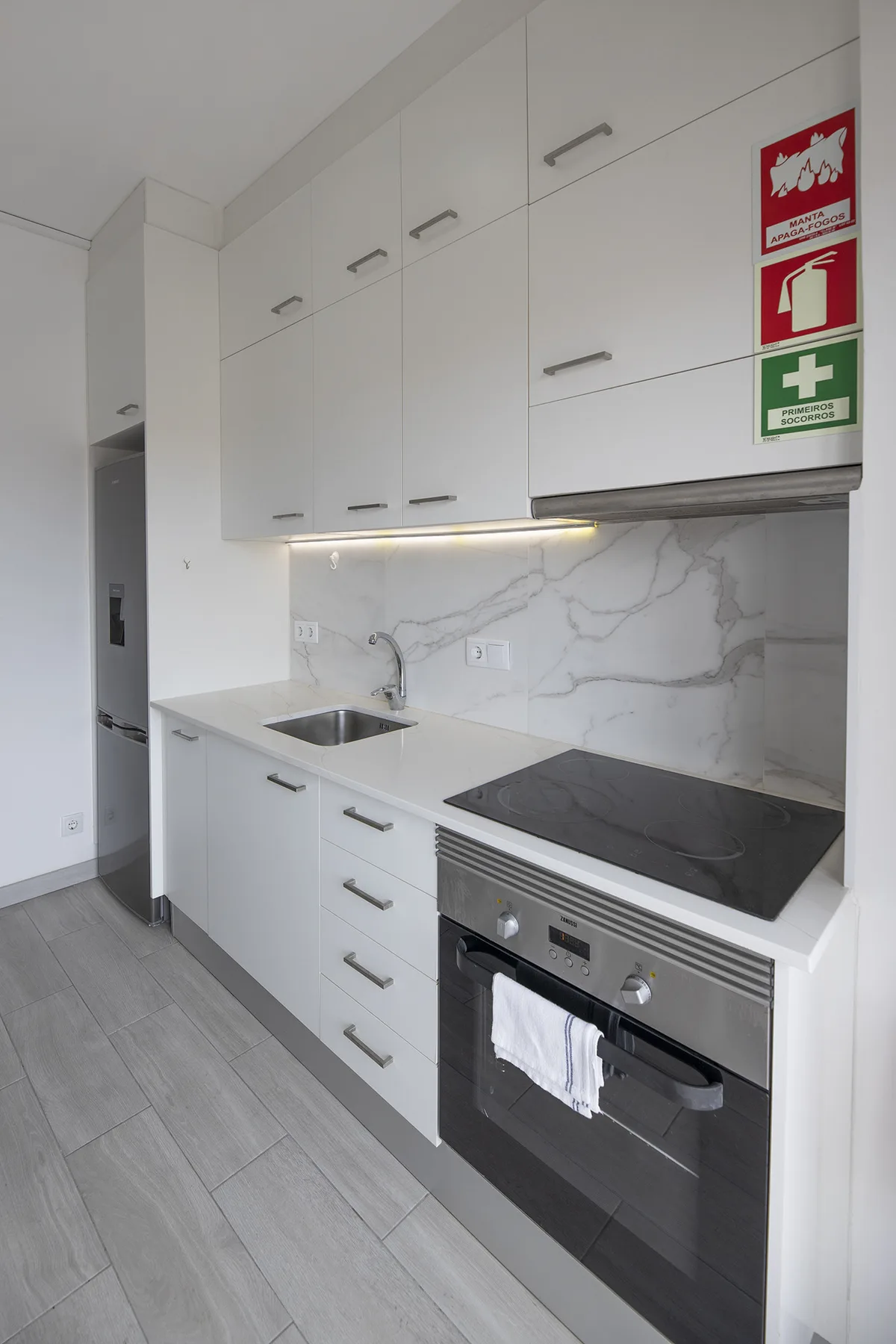 A modern kitchen with white cabinetry, a sink, and a built-in oven.