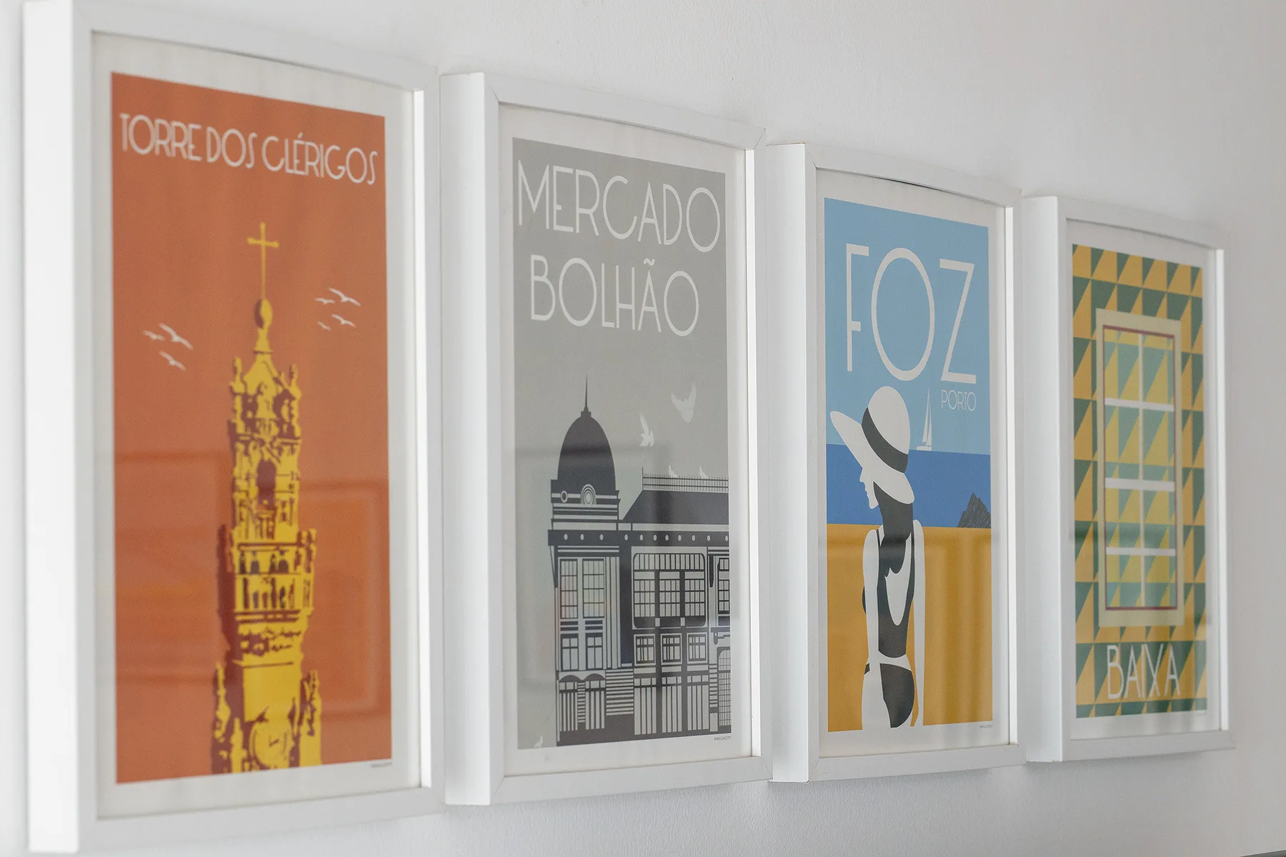 Four framed colorful posters hang in a row on a white wall.