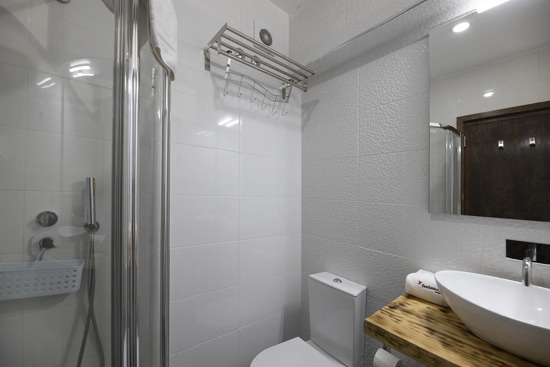 A bathroom with a glass shower, toilet, and vessel sink on a wooden counter.
