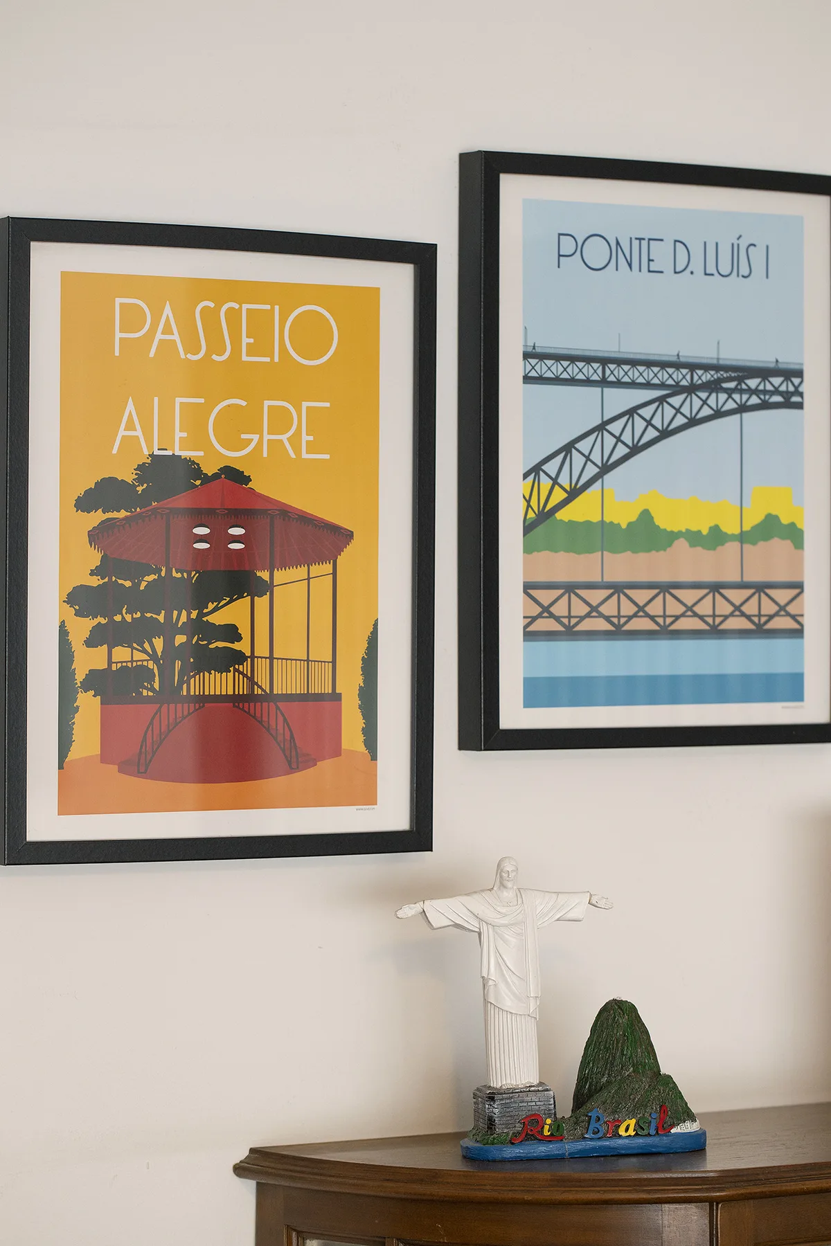 Two framed Porto-themed prints hang above a small decorative display on a wooden shelf.