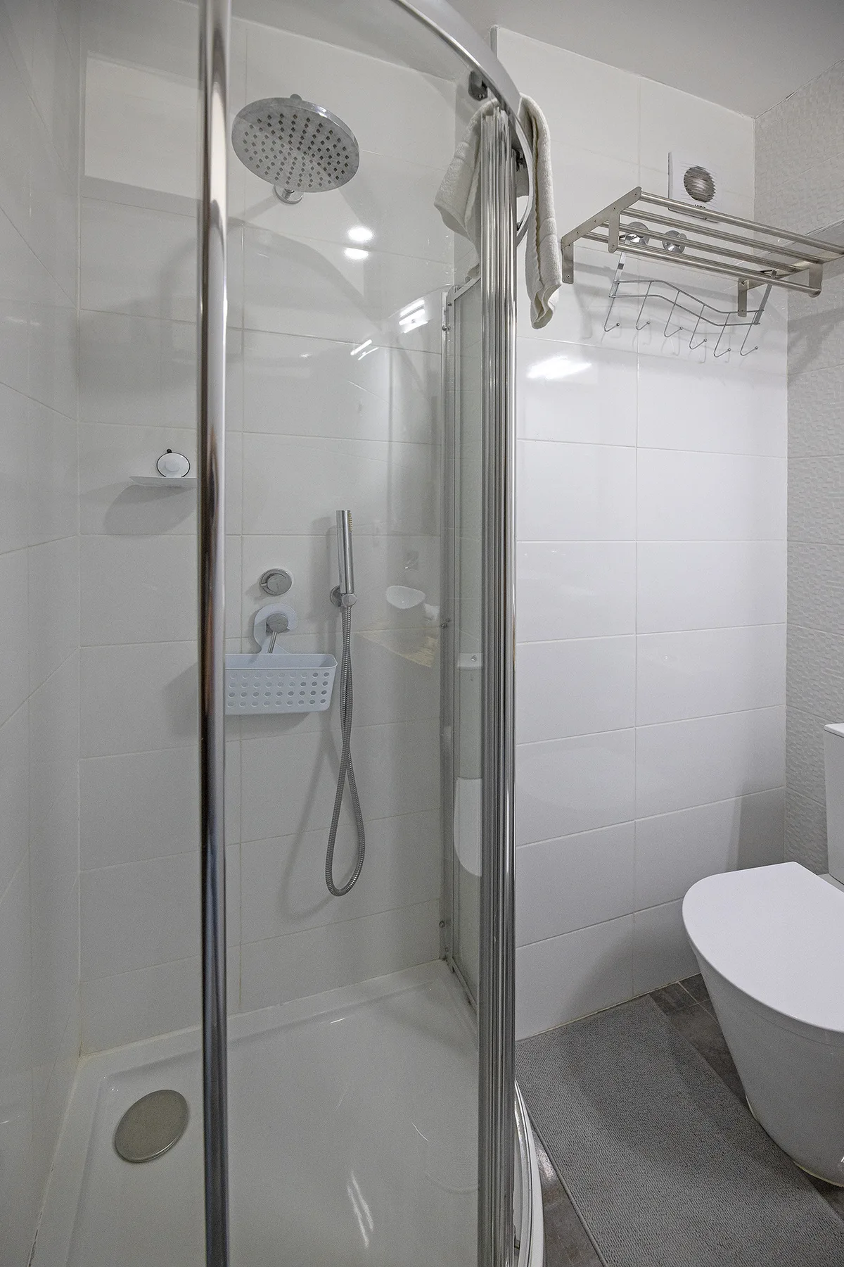 A tiled bathroom with a glass shower and a toilet.