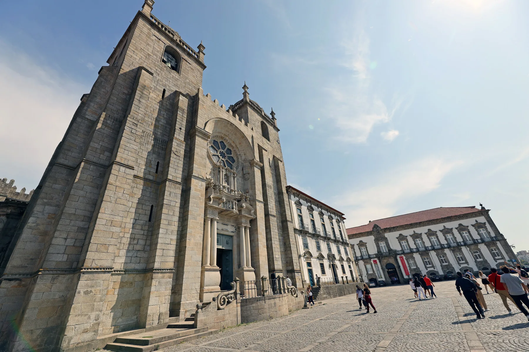A stone church stands beside a paved square with pedestrians.