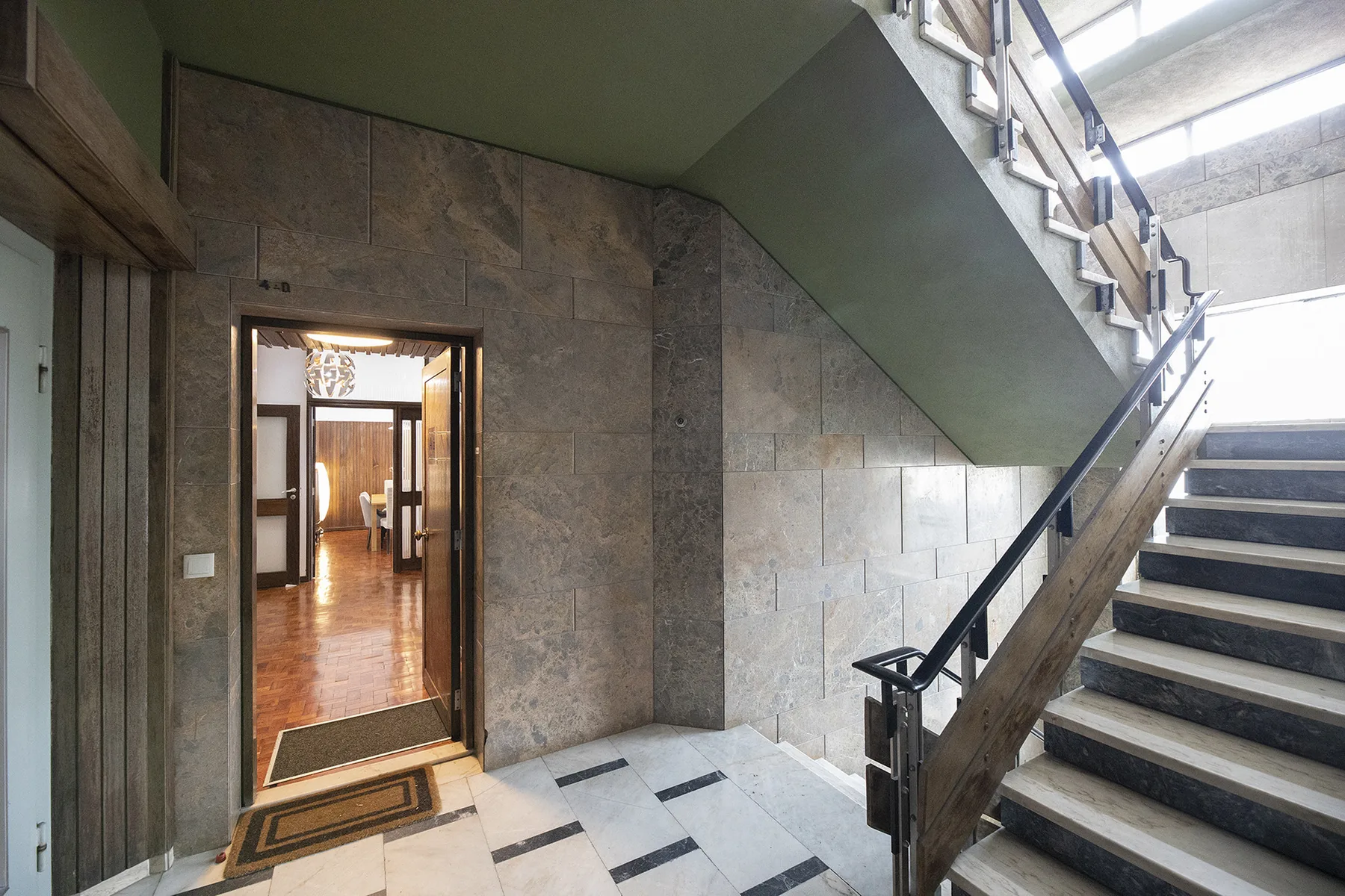 A stone-lined stairwell with stairs beside an open doorway.
