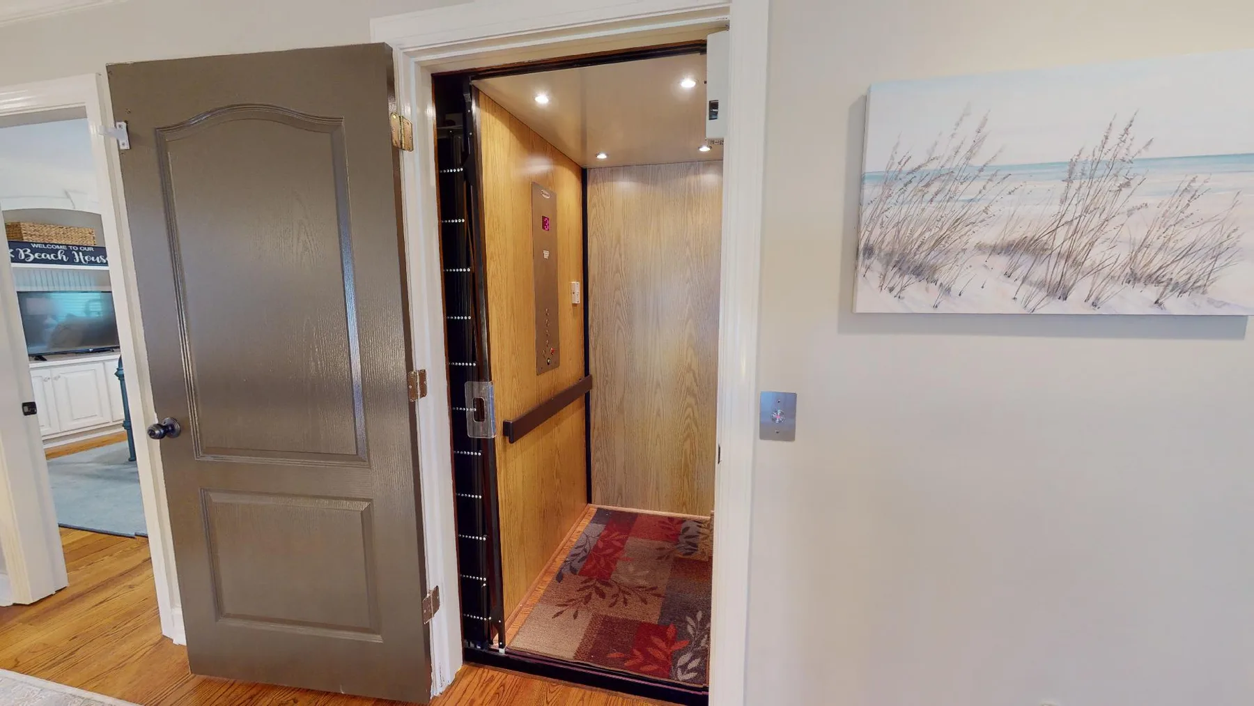An open doorway reveals a warmly lit interior hallway with a patterned rug.