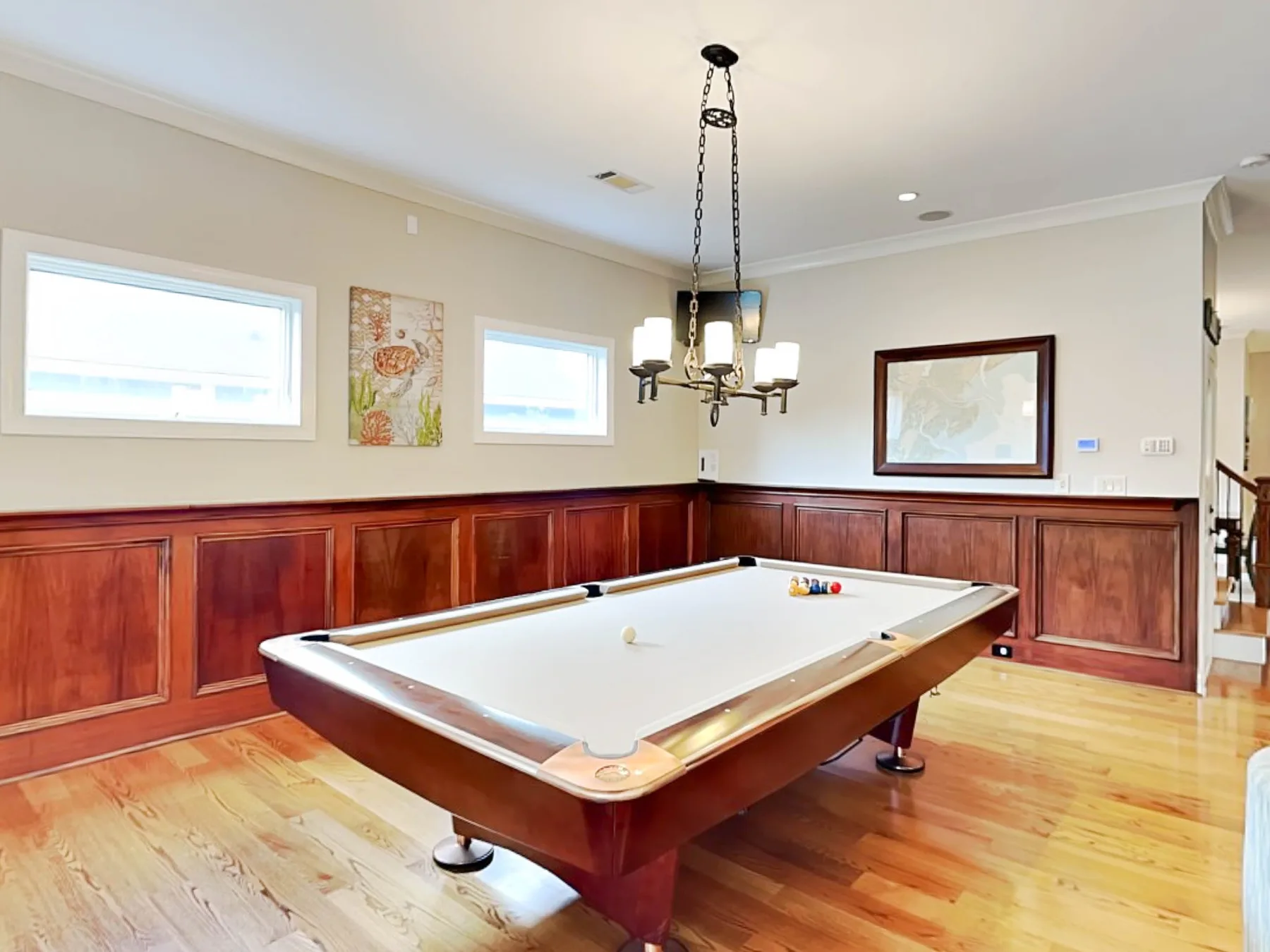 Una sala de billar con una mesa de pool y paredes revestidas de madera.