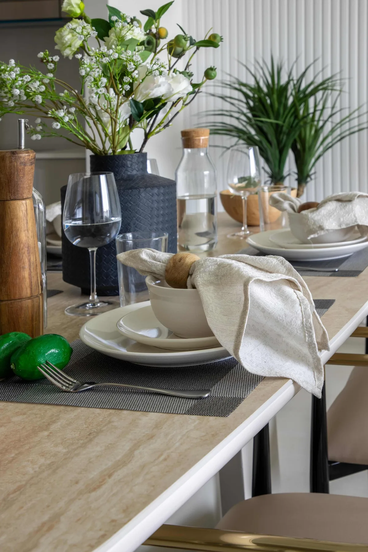 A dining table is set with plates, glasses, and a vase of flowers.
