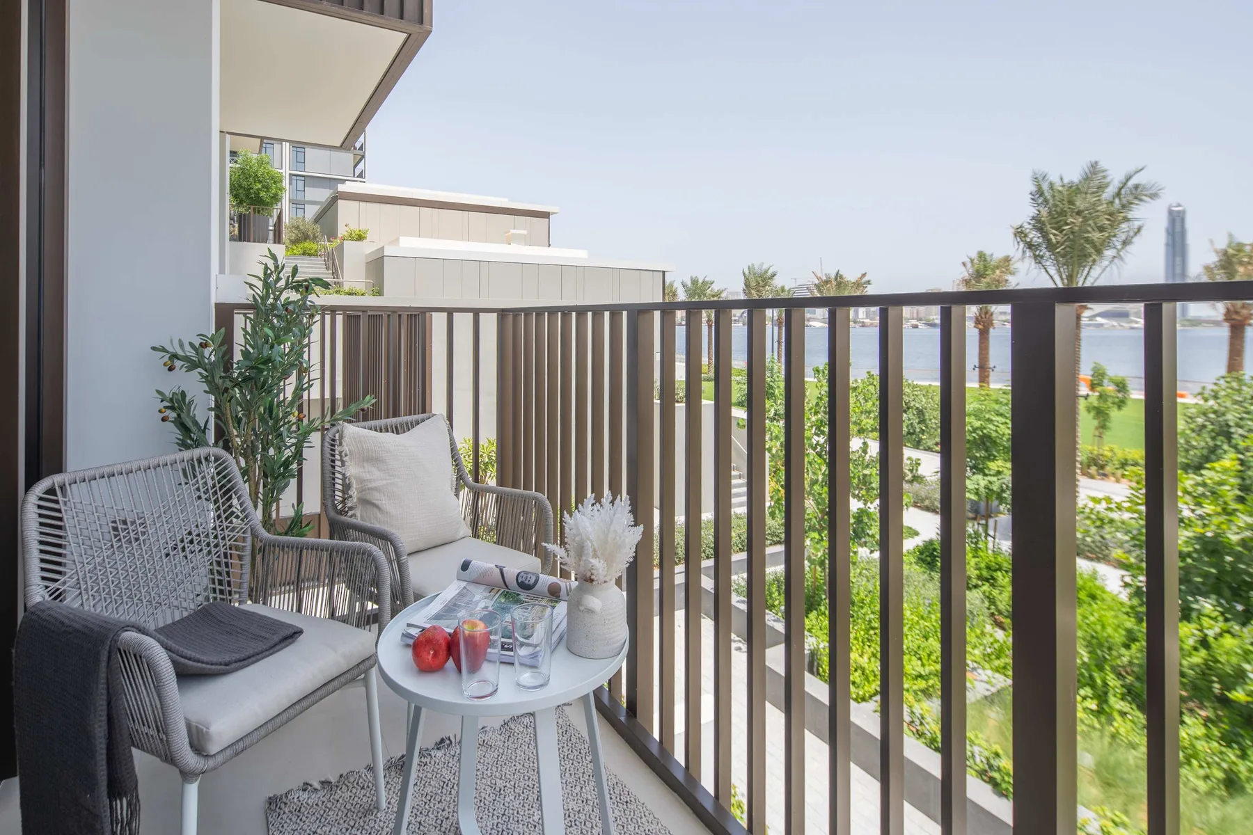 A balcony seating area overlooks green landscaping and the water.