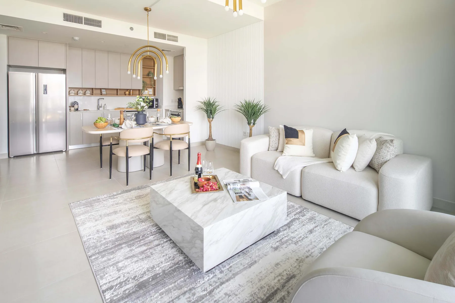A bright open-plan living room with a dining table and kitchen.