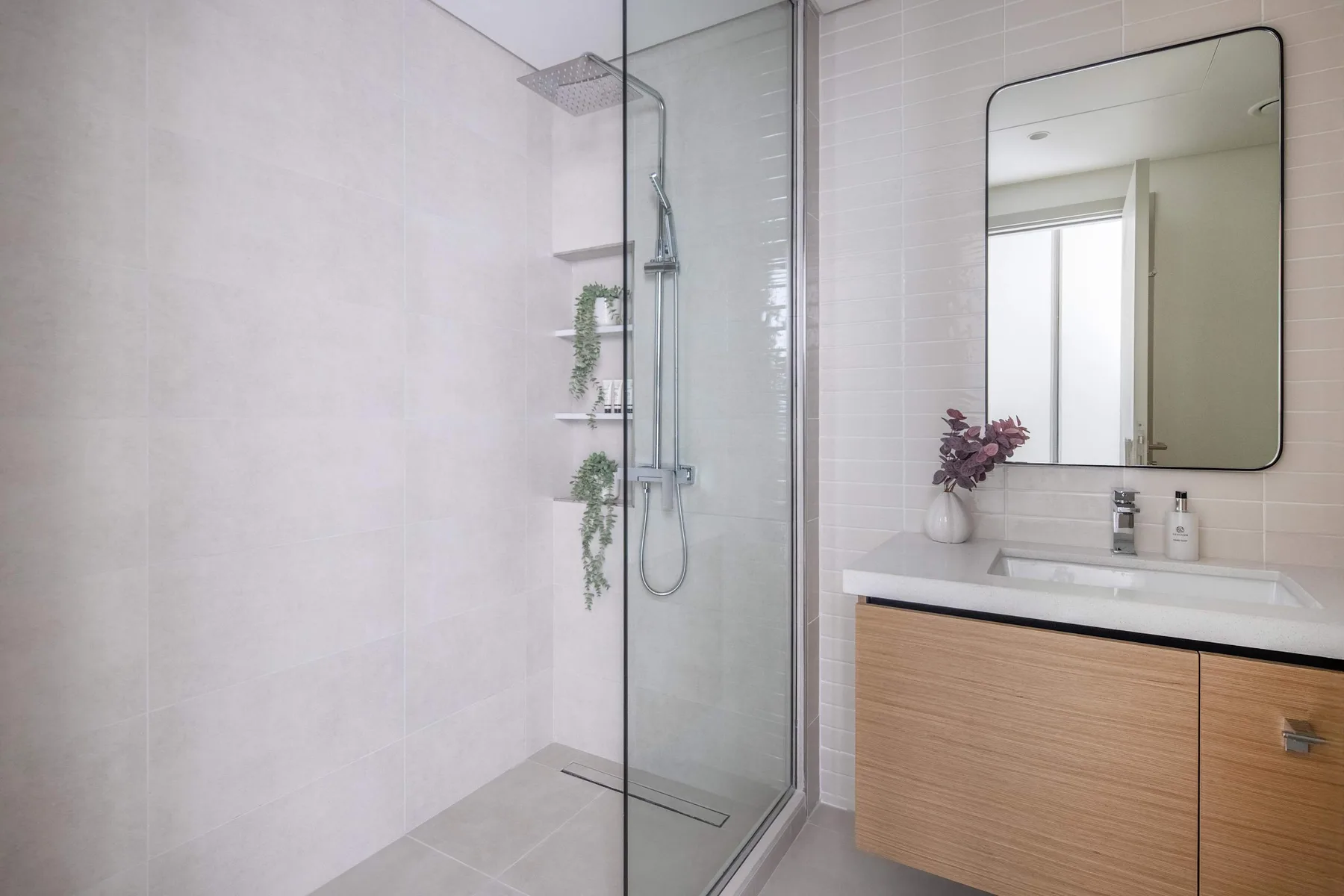 A bright bathroom with a glass shower and a vanity beneath a wall mirror.