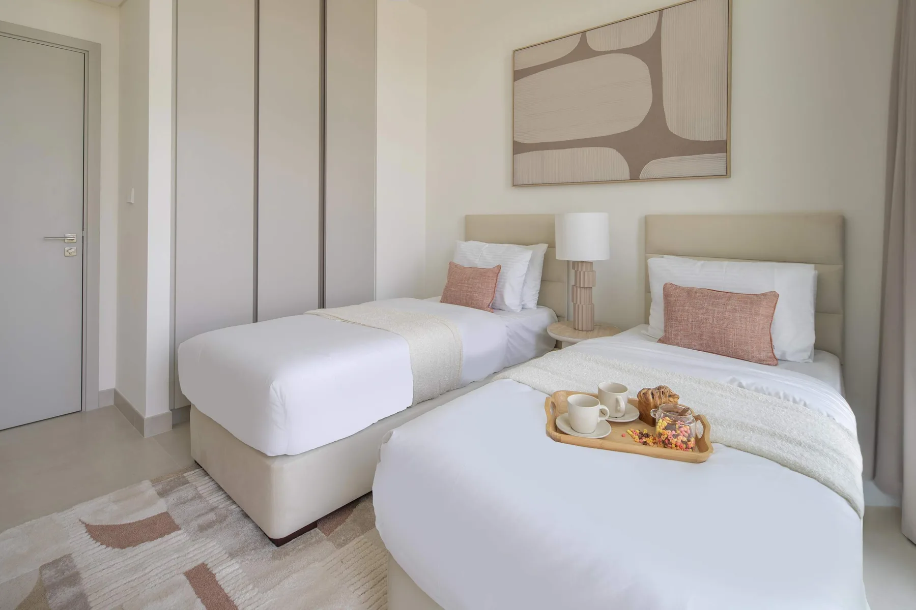 A bright bedroom with two beds and a small bedside table.