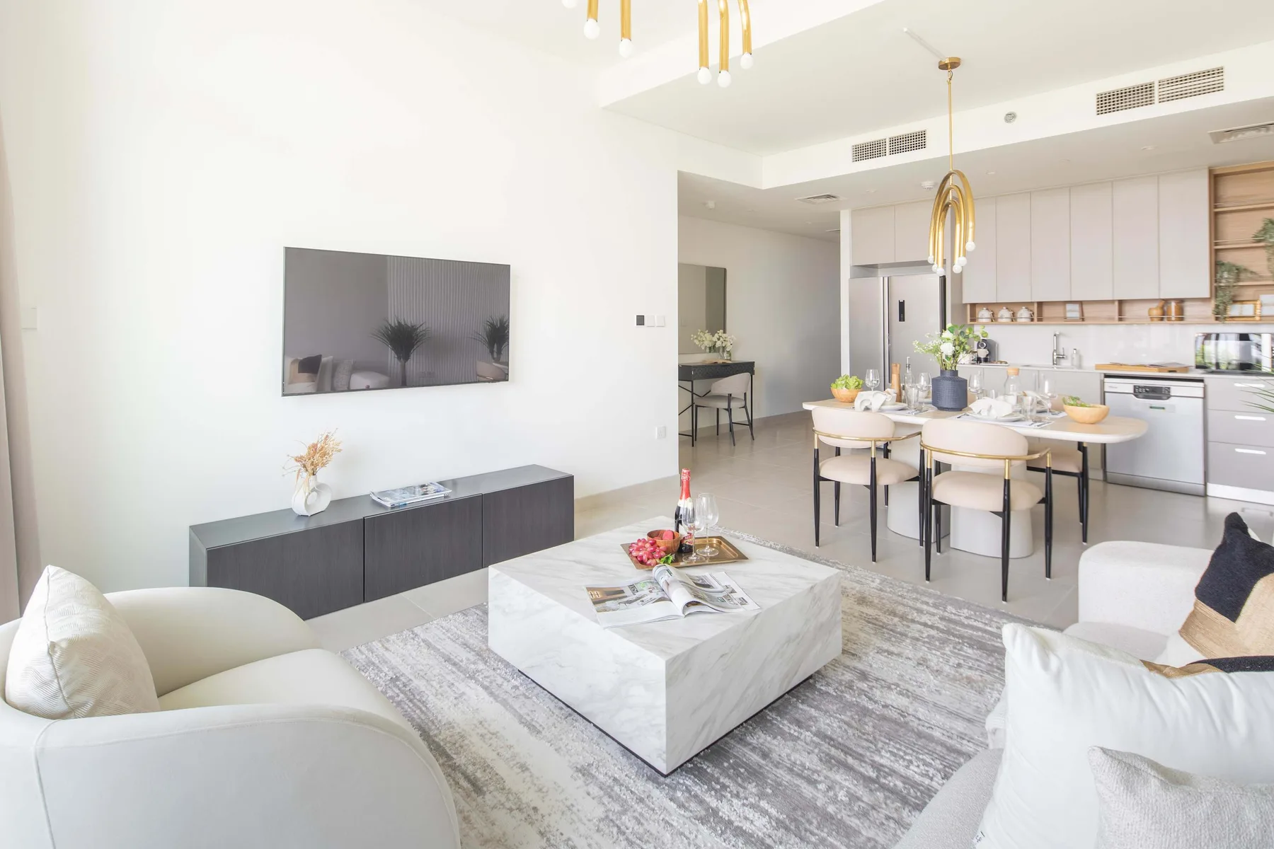 A bright open-plan living and dining area with a kitchen and marble coffee table.