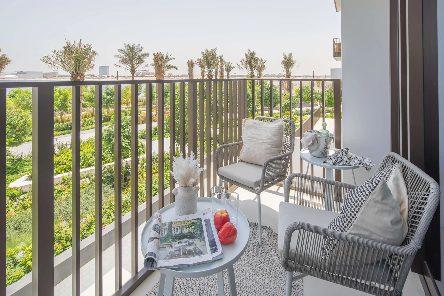 A balcony seating area overlooks landscaped greenery, with small tables beside the railing.