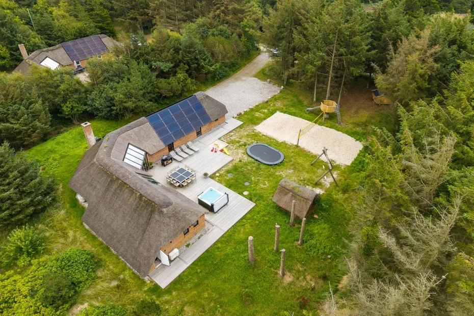 Vista aérea de una casa y una zona de juegos al aire libre rodeadas de árboles.