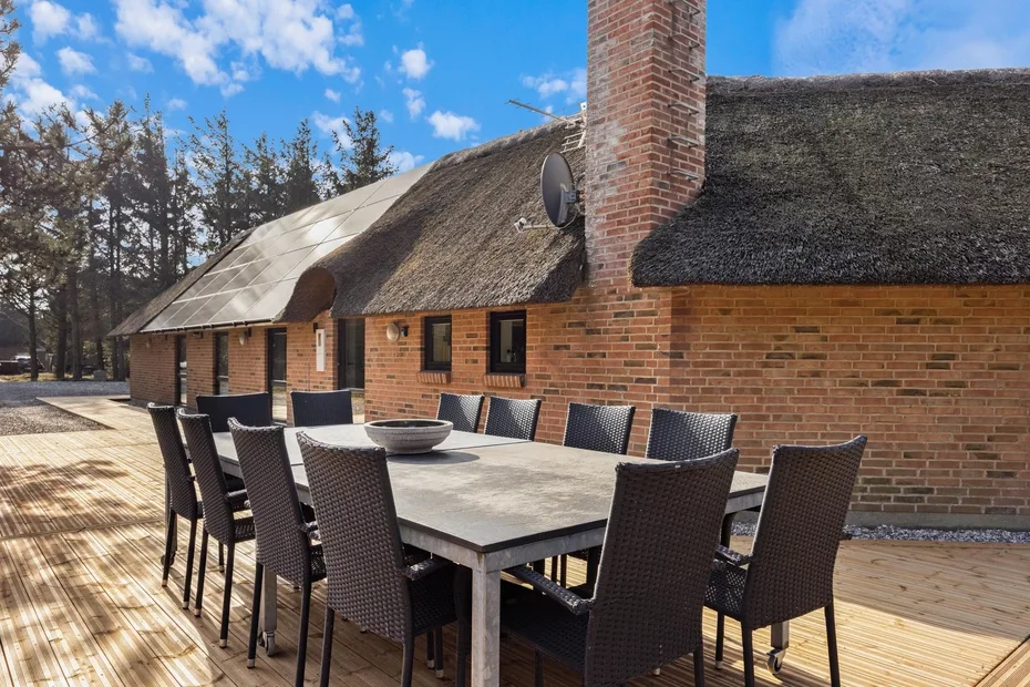 Comedor al aire libre en una terraza de madera junto a un edificio de ladrillo.