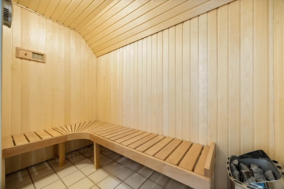 Una sauna revestida de madera, con asientos escalonados y un calentador de piedras.