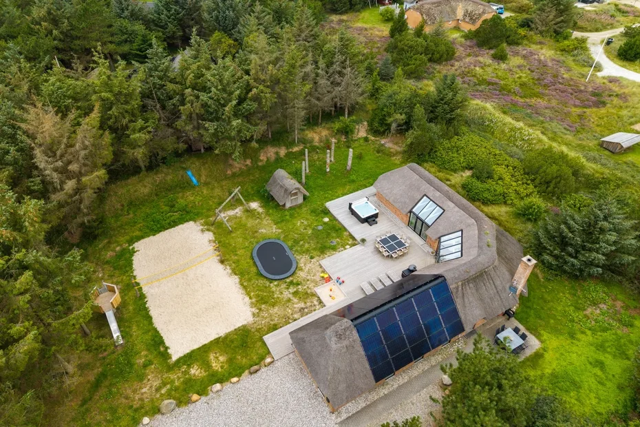 Una vista aérea muestra una casa con paneles solares entre un denso bosque verde.
