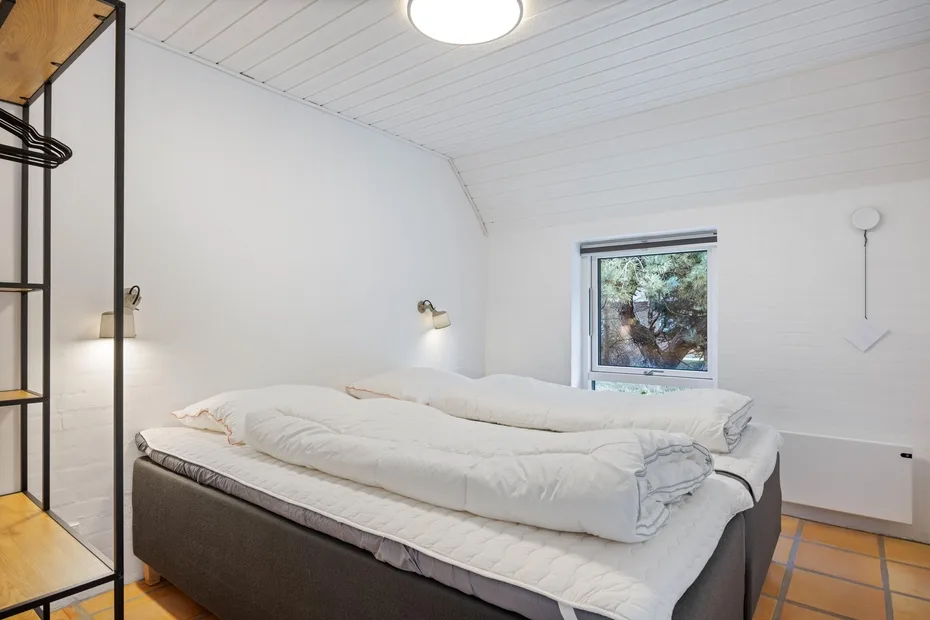 Un dormitorio con una cama grande, ropa de cama blanca y una ventana.