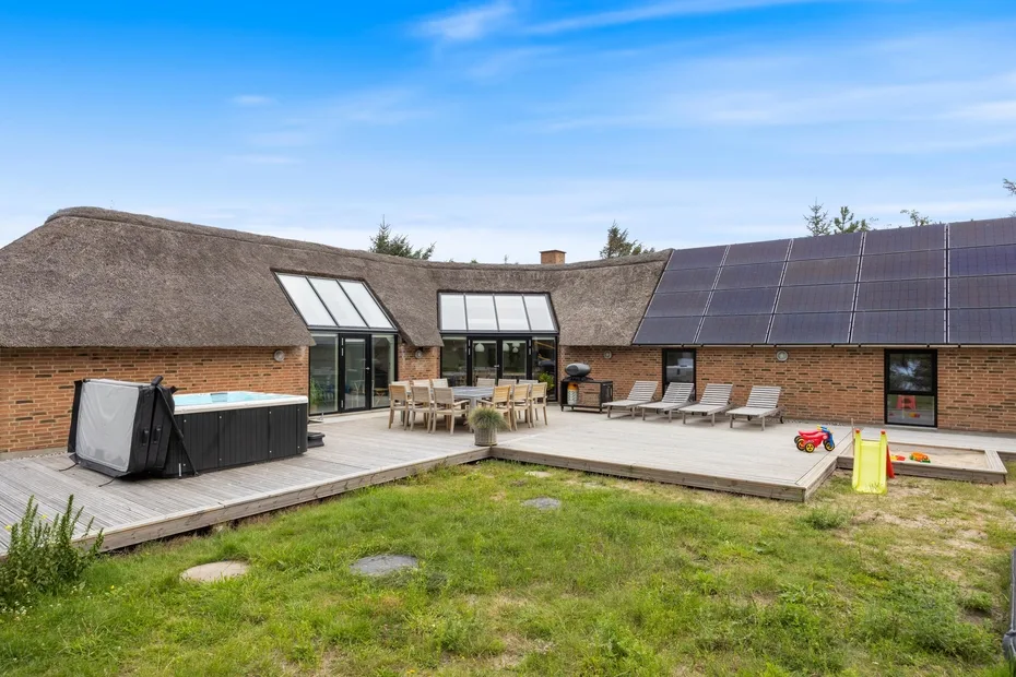 Un patio interior con asientos al aire libre, una bañera de hidromasaje y paneles solares en el tejado.
