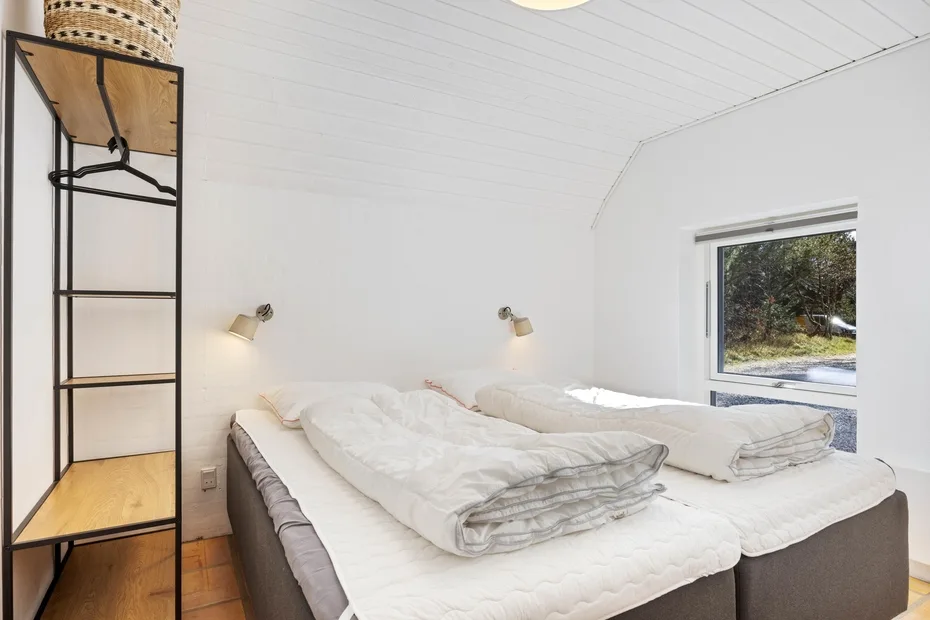 Un dormitorio con dos camas bajo un techo blanco inclinado.