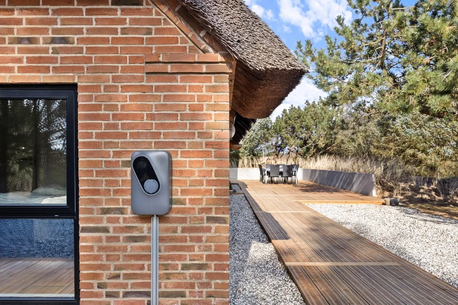 Una terraza de madera junto a un edificio de ladrillo conduce a una zona de estar al aire libre.