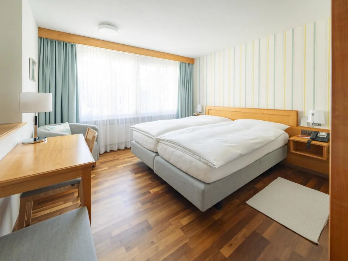 Bright room with a double bed, sitting area and parquet flooring.