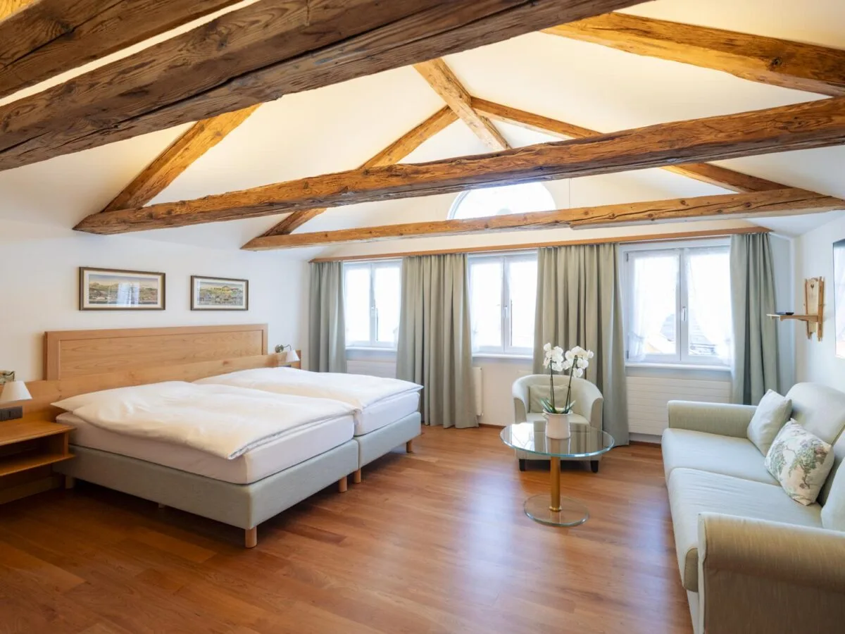 Family Junior Suite with large windows, a sitting area and double bed.