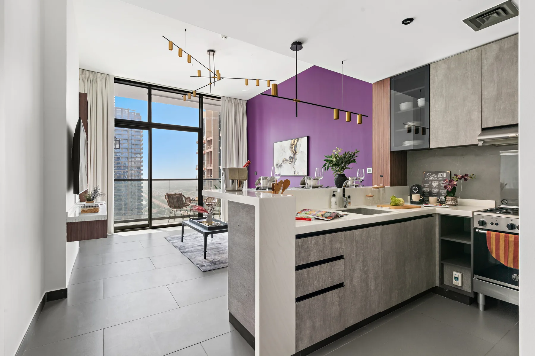 Una cocina abierta al salón, con una pared morada y grandes ventanales.