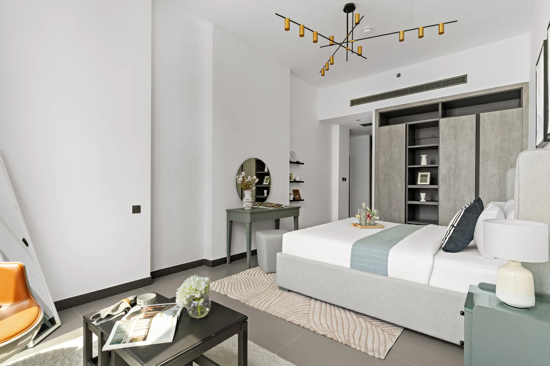 Un dormitorio luminoso con una cama, mesitas de noche y un armario grande.