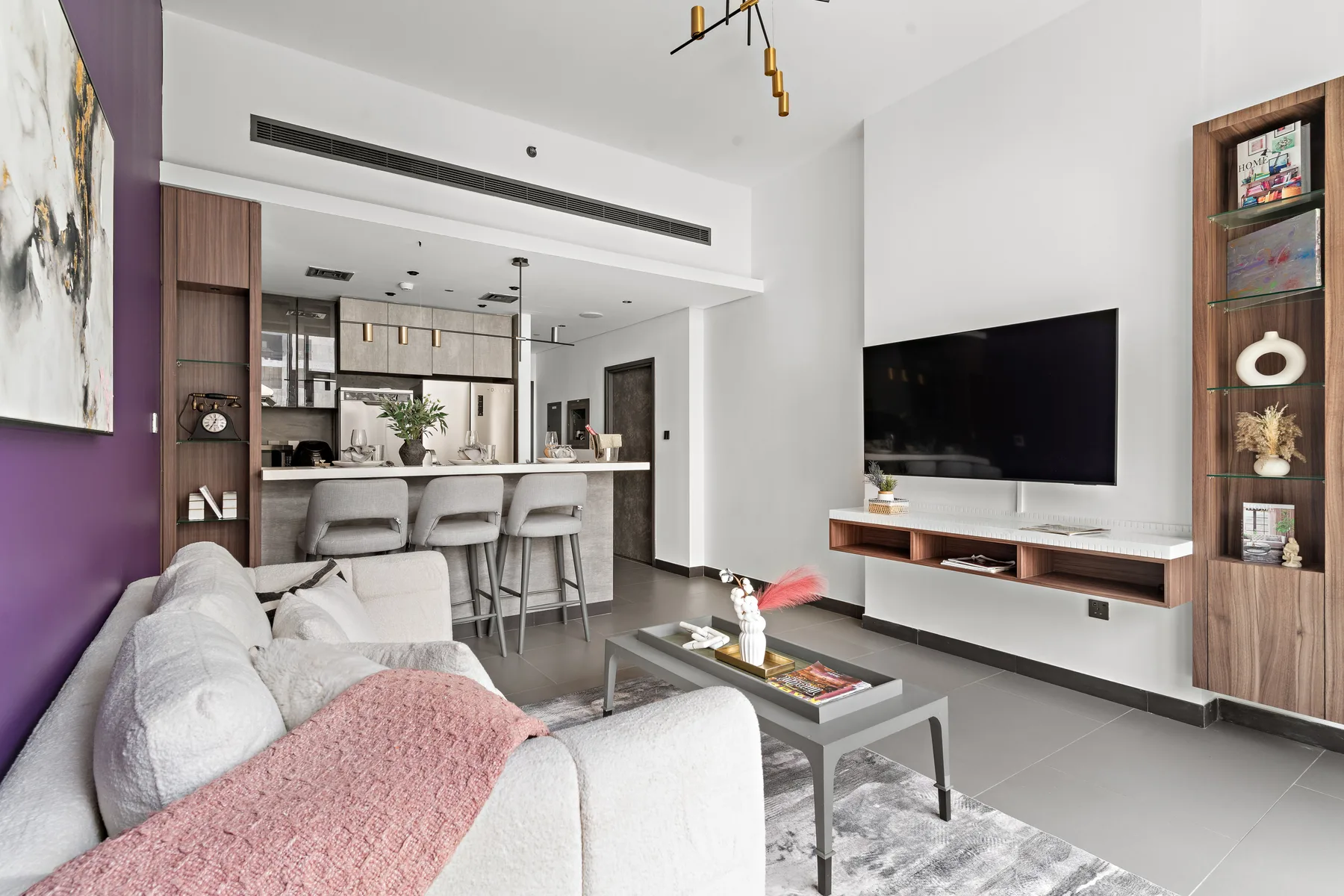 Una sala de estar moderna con asientos, un televisor y una cocina abierta.