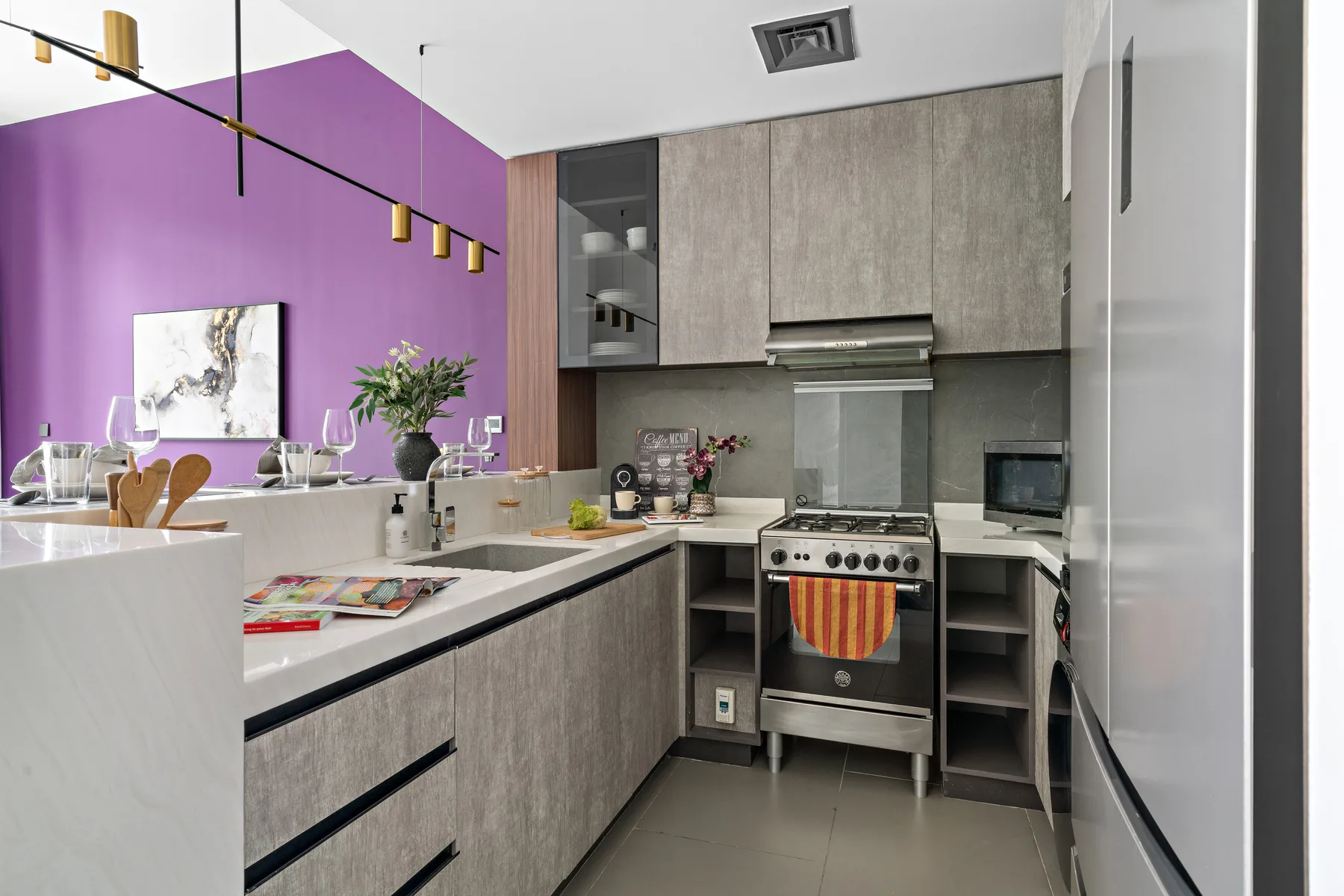 Una cocina moderna con gabinetes grises, una estufa y una pared morada.