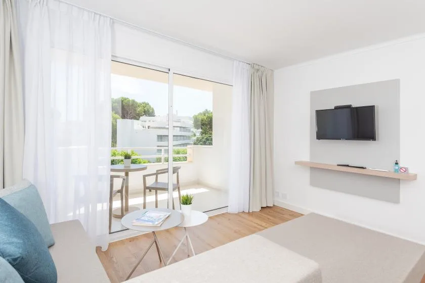 A bright living room opens onto a balcony through wide glass doors.