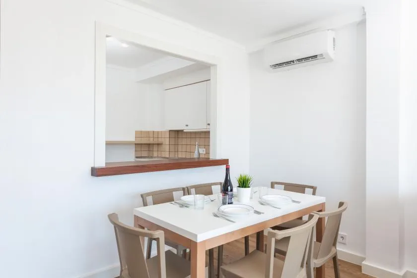 A dining area with a table and chairs beside a kitchen pass-through.