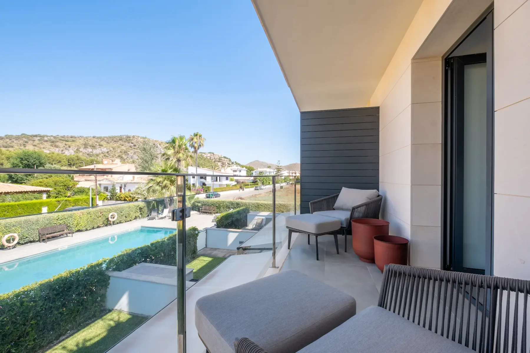 A balcony with outdoor seating overlooks a landscaped pool area.