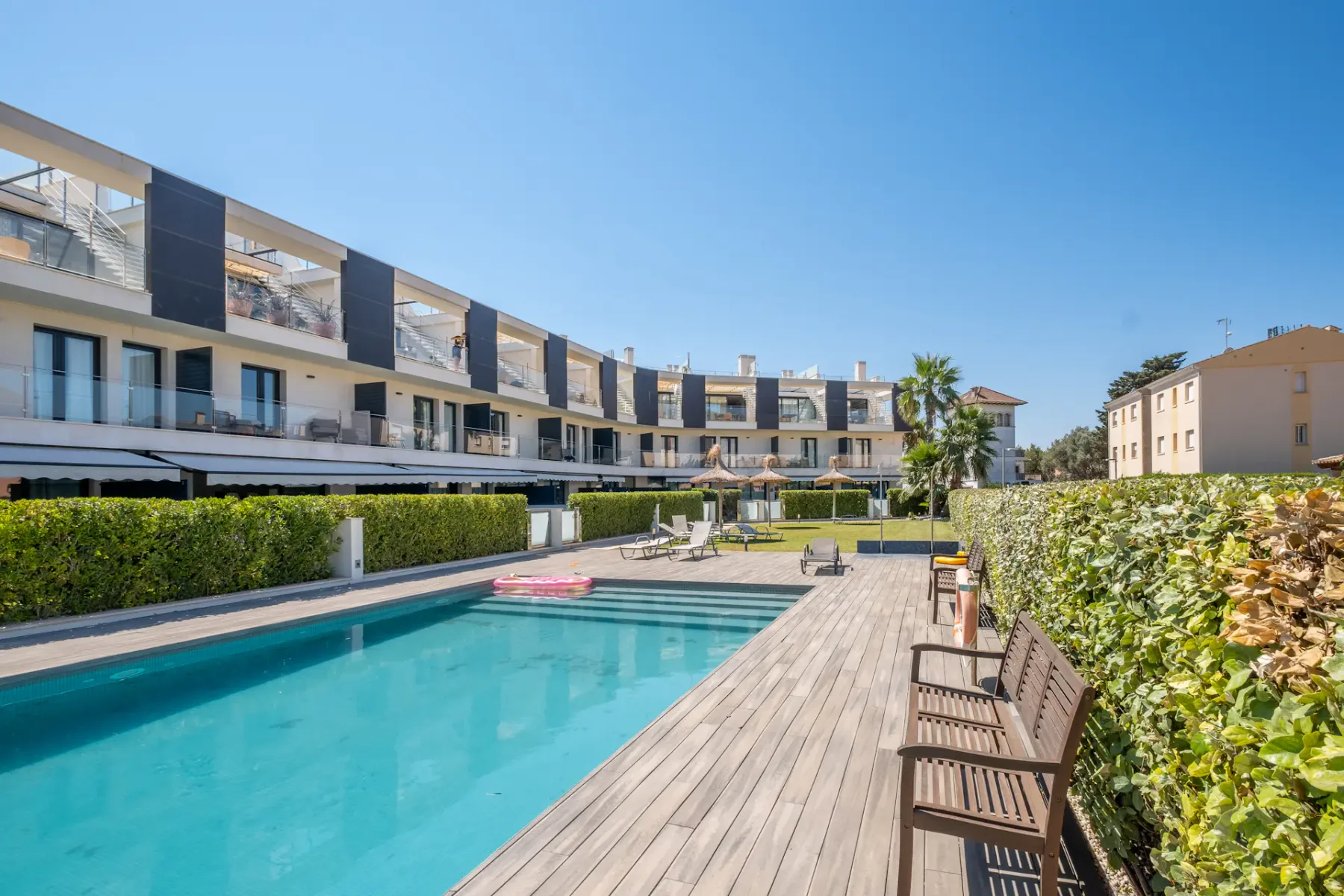 A rectangular swimming pool beside a wooden deck and rows of seating.