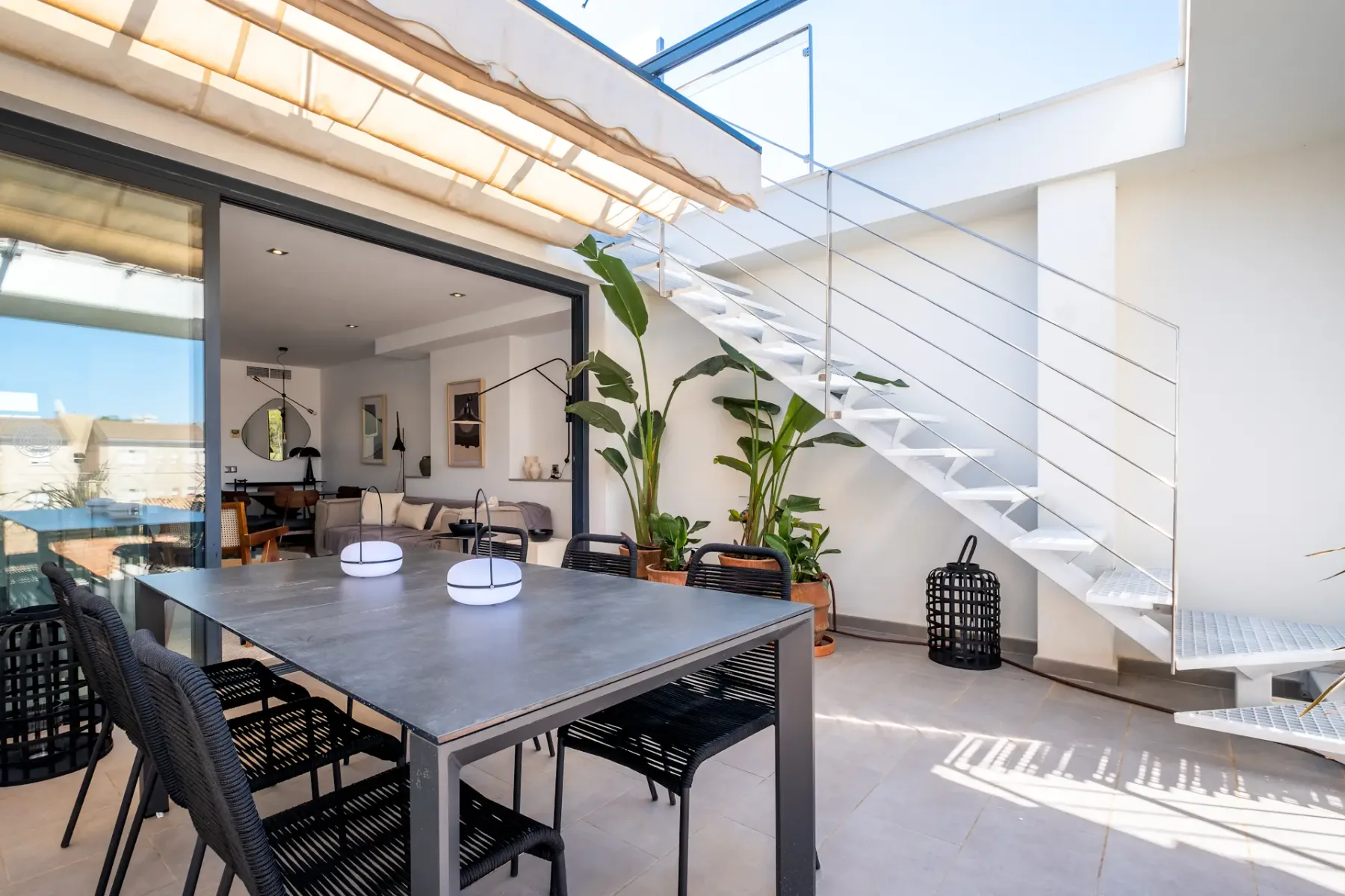 An outdoor dining area with a large table and stairs beside it.