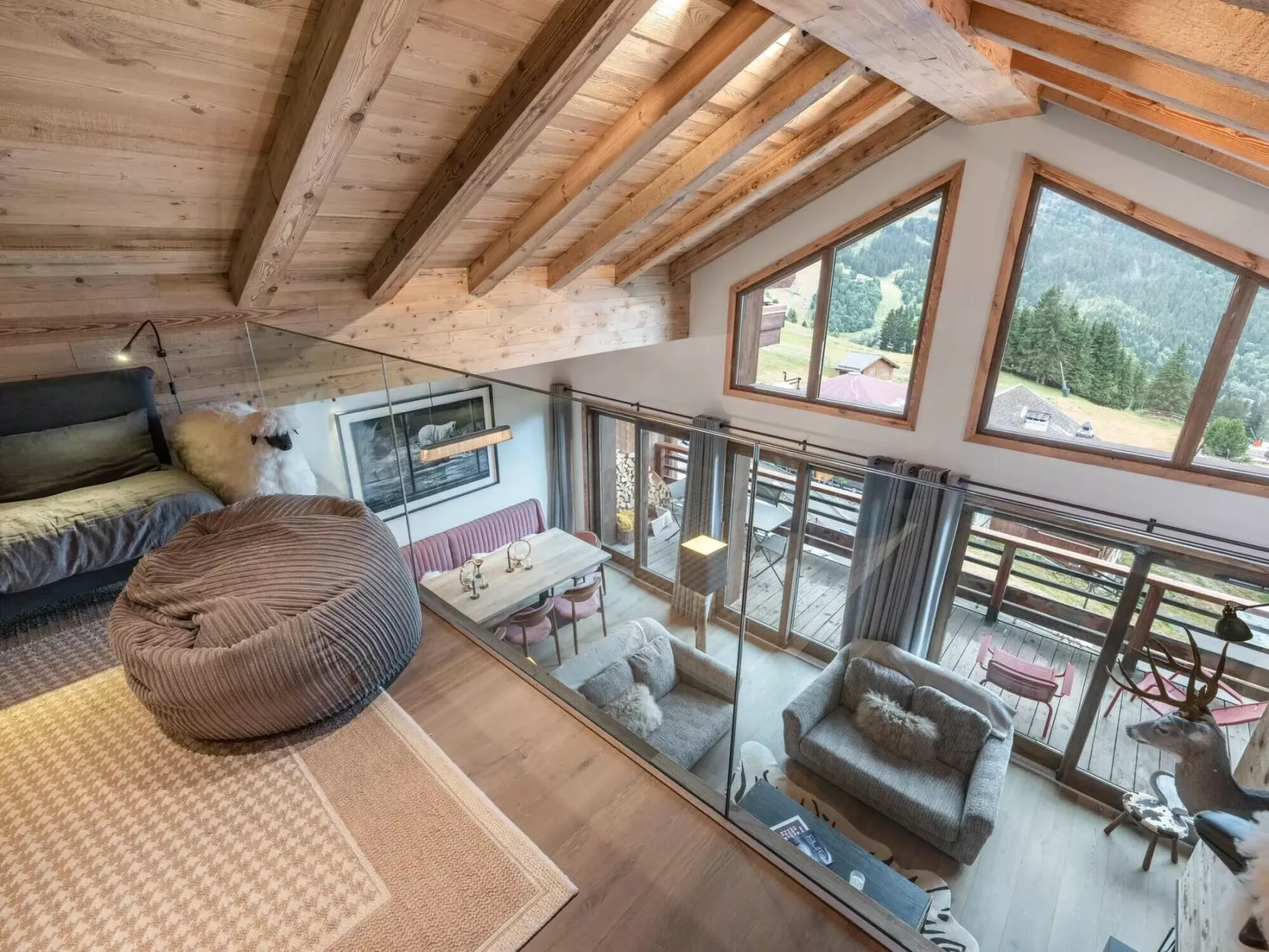 A loft-style living room with a sleeping area, seating, and large windows.