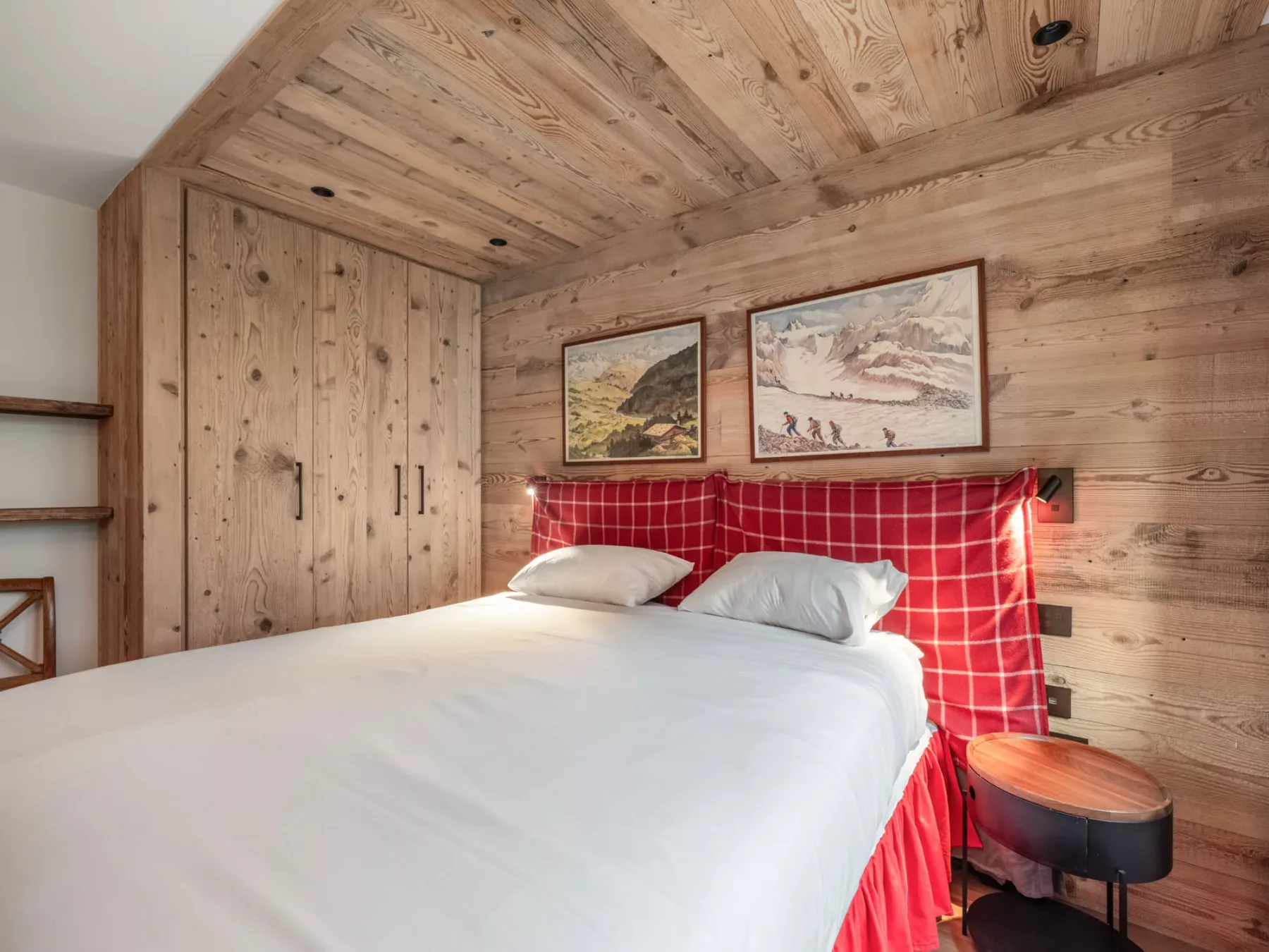 A bedroom with a bed, red checked headboard, and wood-paneled walls.