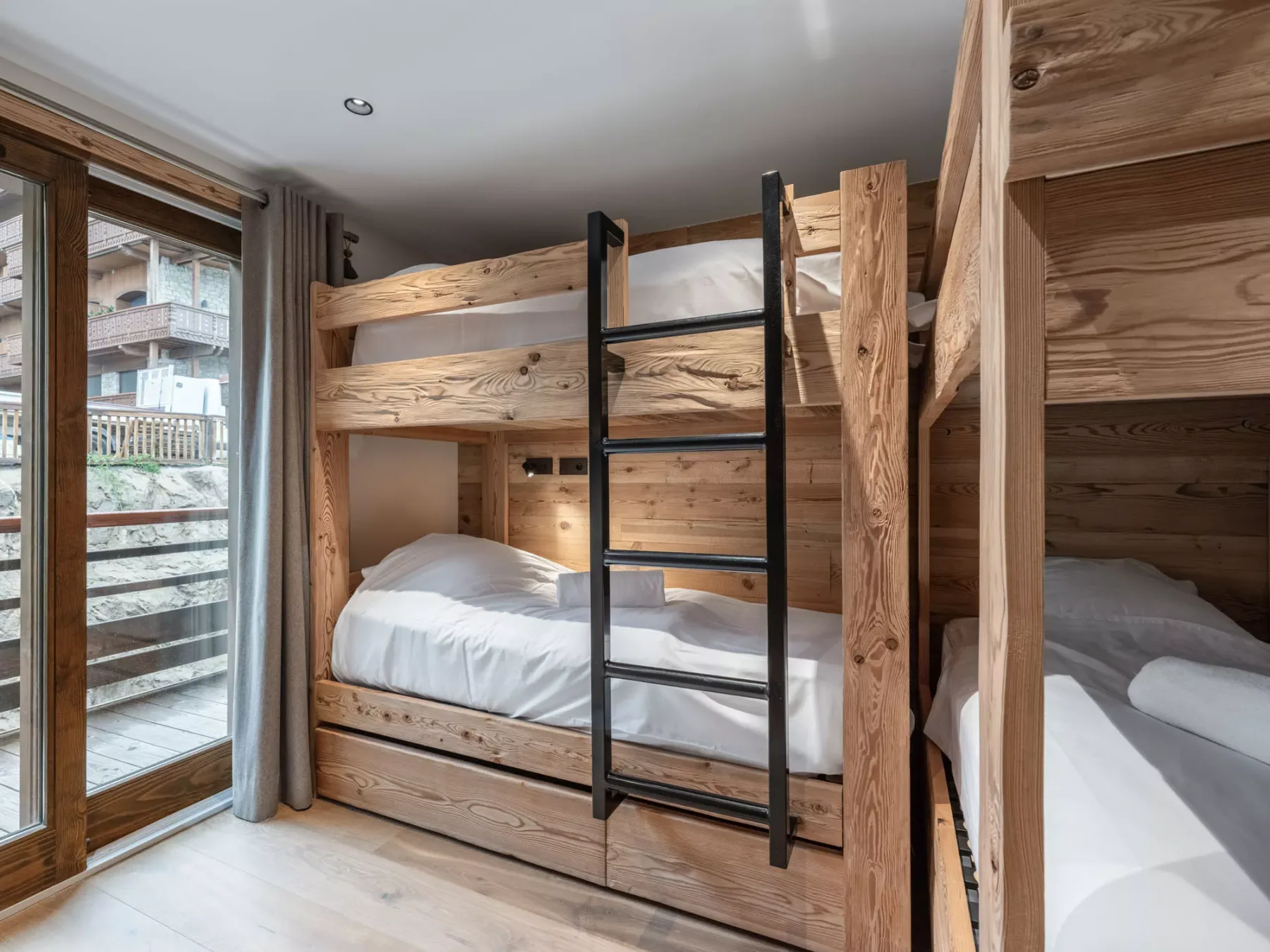 A wood-paneled bedroom with bunk beds and a large window.